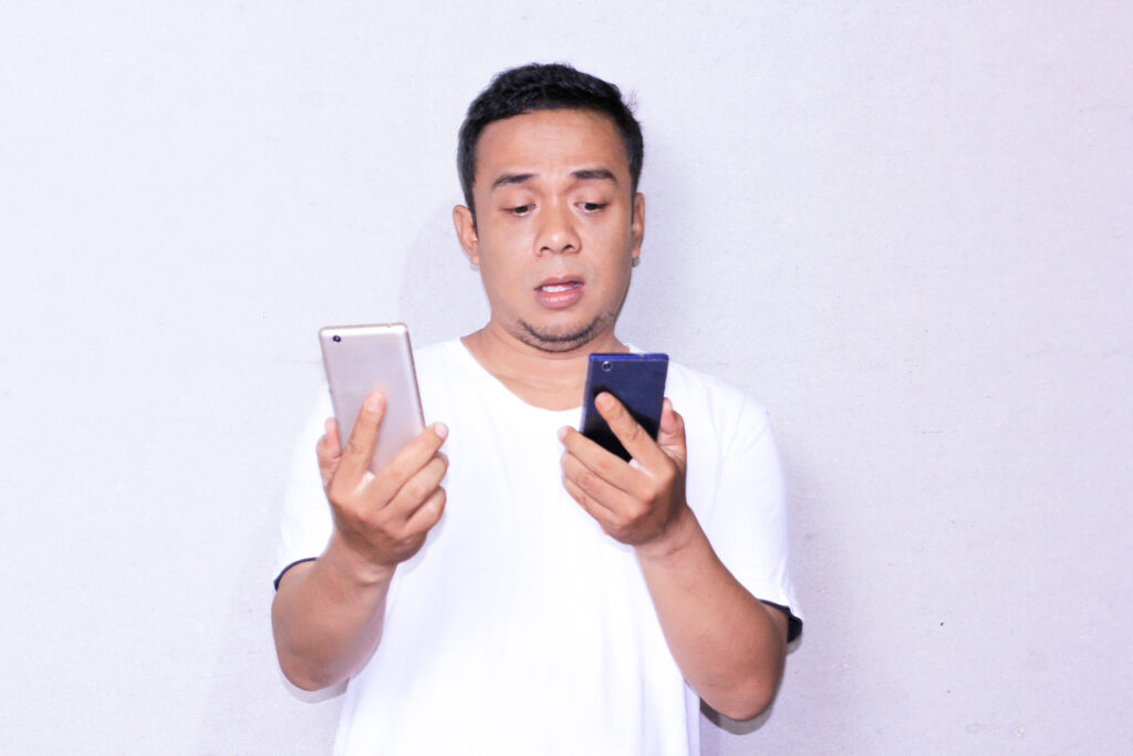 Man choosing the right phone between two options, looking confused