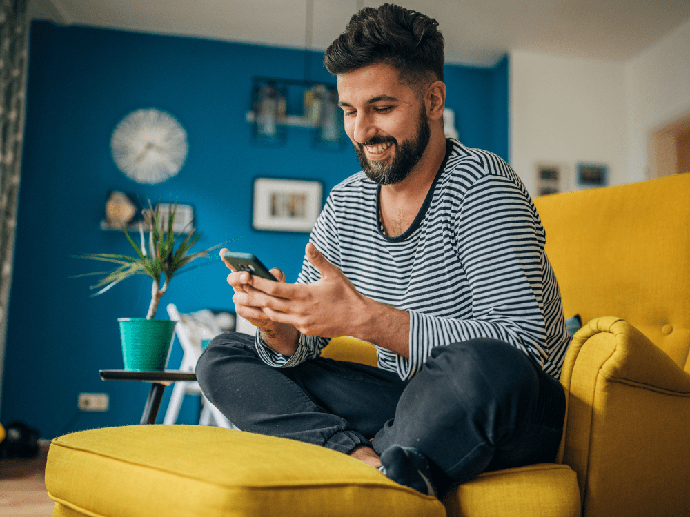 Happy man using refurbished phone in vibrant room