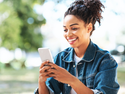Girl smiling looking at phone outdoors