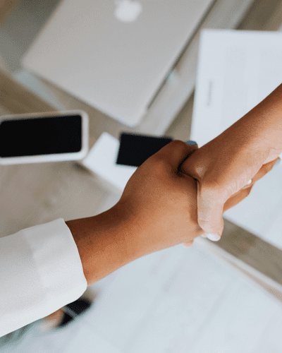 People handshaking on top of table with refurbished phones on