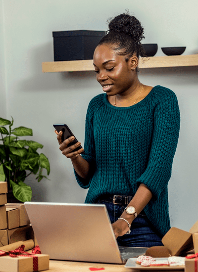 Woman looking at phone with hand on laptop