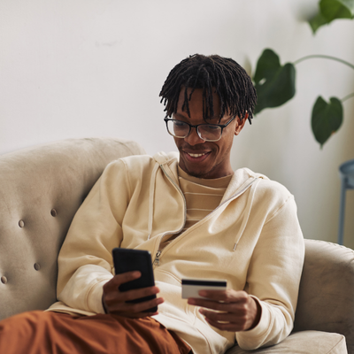 Man smiling at phone with bank card in hand
