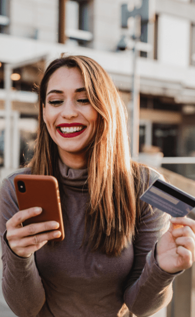 Woman smiling with phone and bank card in hands